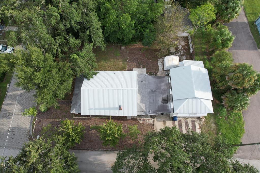 An aerial view shows a house with a metal roof surrounded by trees and pavement — 6506 N WELLINGTON AVENUE, TAMPA, FL