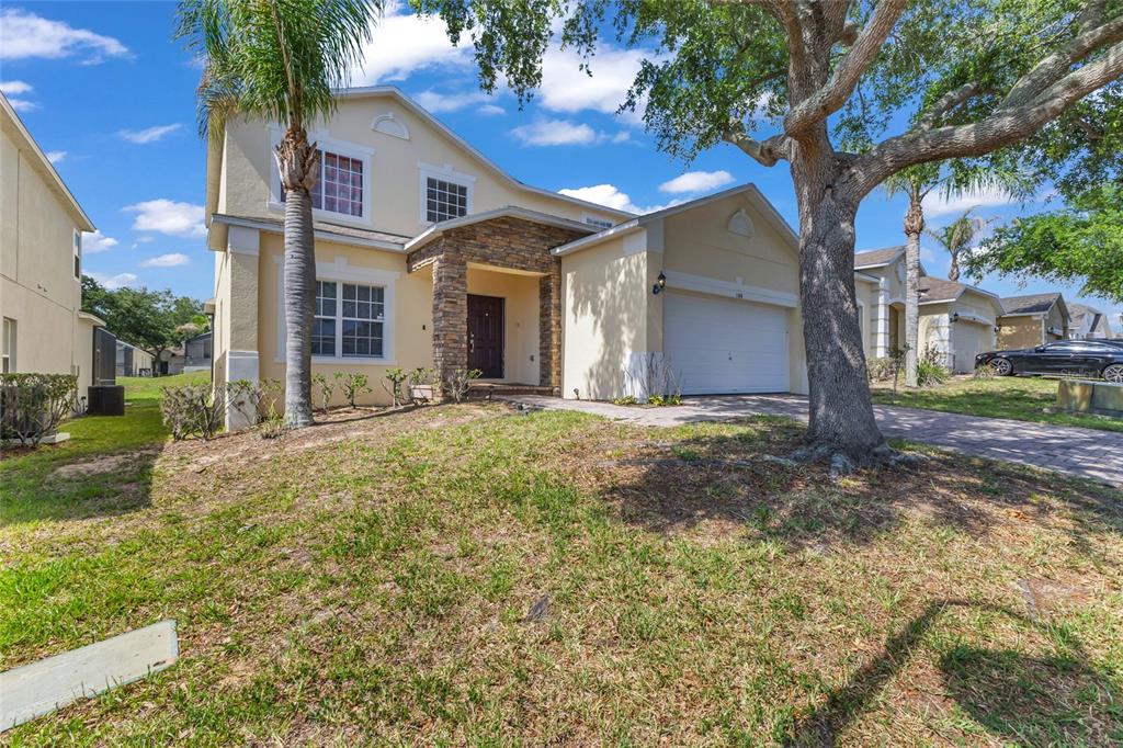 A two-story house with a stone-accented entryway, a two-car garage, and a large front tree — 164 LANCASTER DRIVE, DAVENPORT, FL