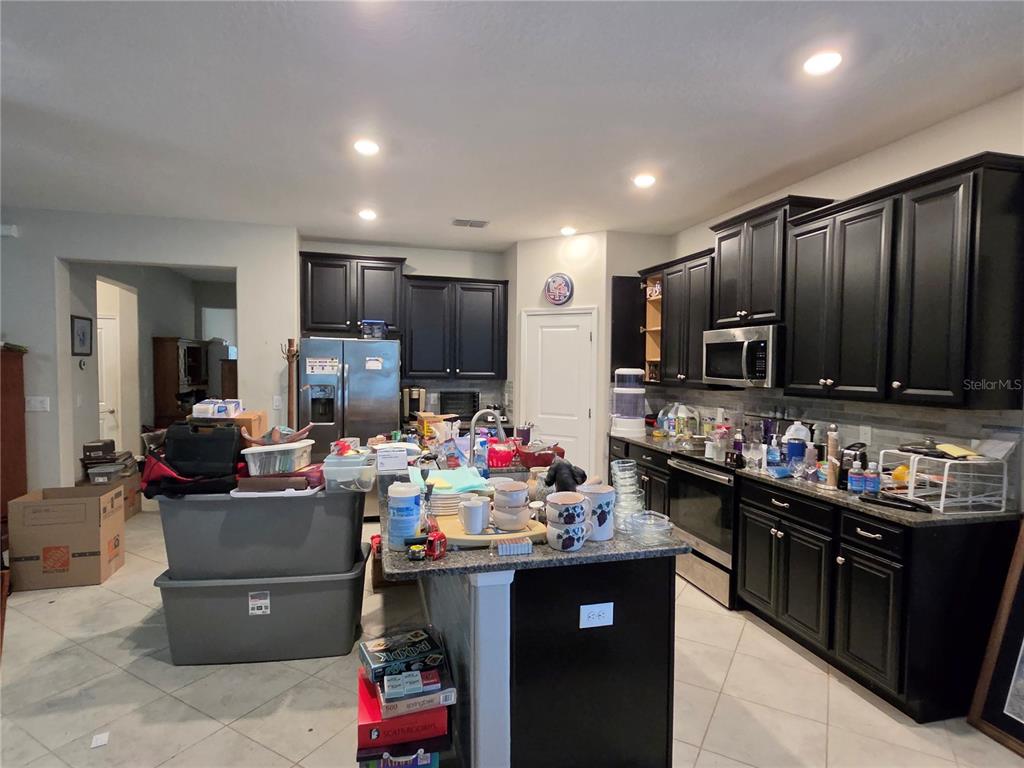 A kitchen with dark cabinets, granite countertops, stainless steel appliances, and a central island — 16842 SCUBA CREST STREET, WIMAUMA, FL