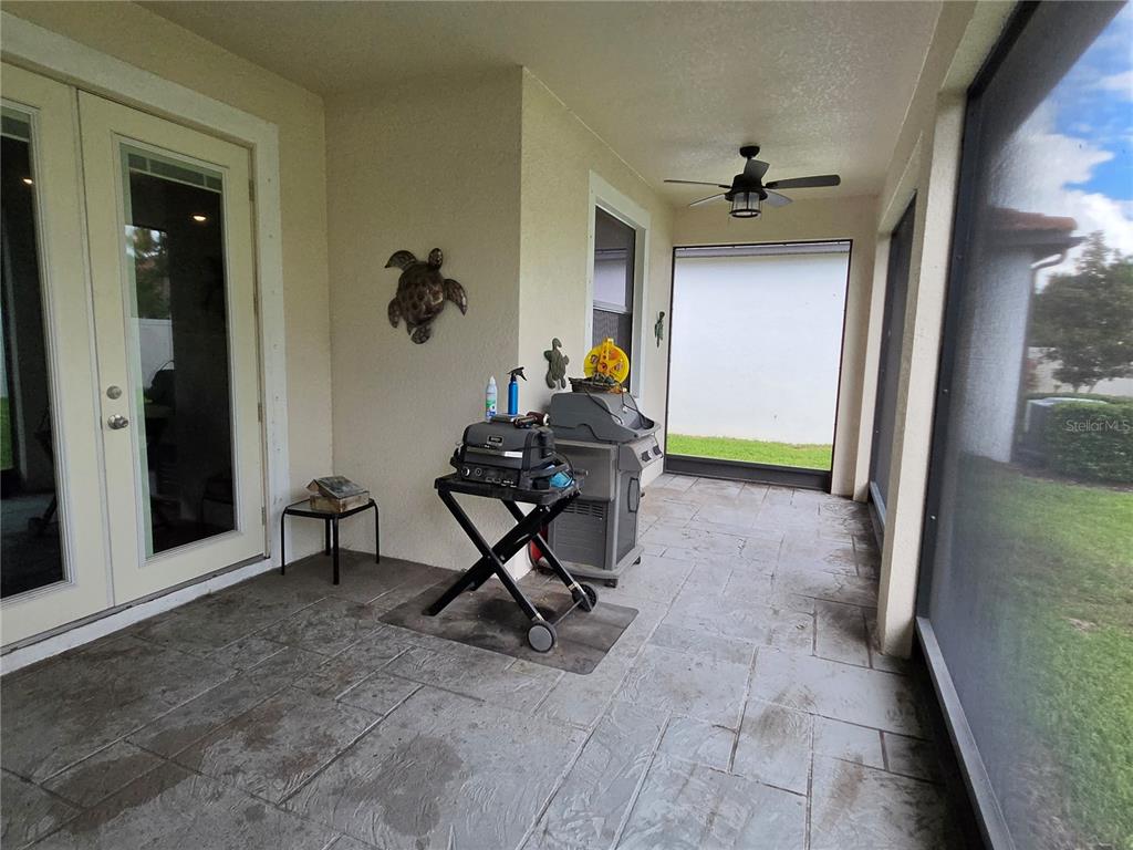A covered patio features a tiled floor, a ceiling fan, and a grill — 16842 SCUBA CREST STREET, WIMAUMA, FL