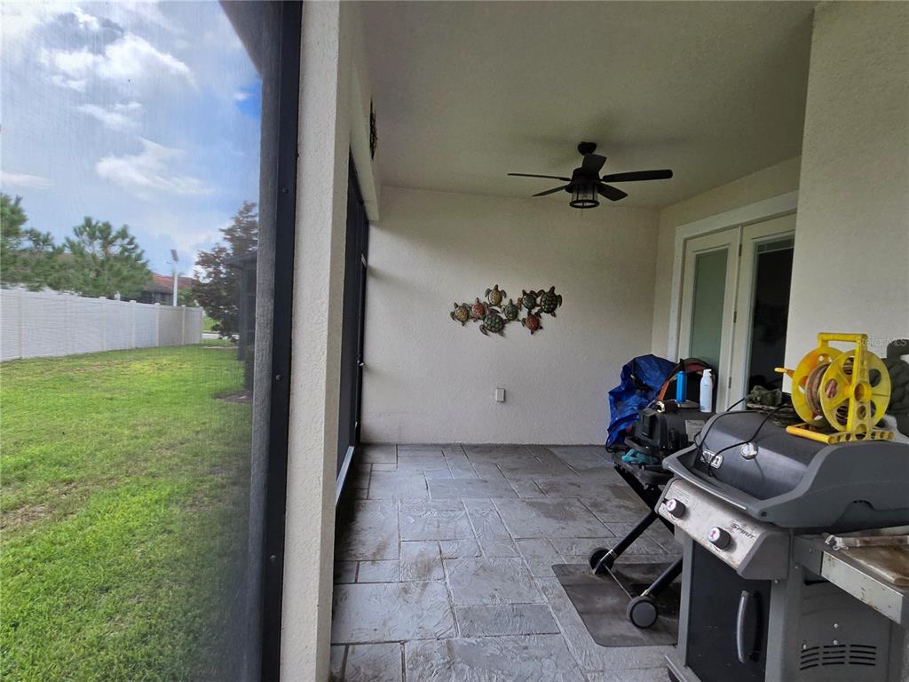 A covered patio with a tiled floor, a ceiling fan, and a grill overlooks a yard — 16842 SCUBA CREST STREET, WIMAUMA, FL