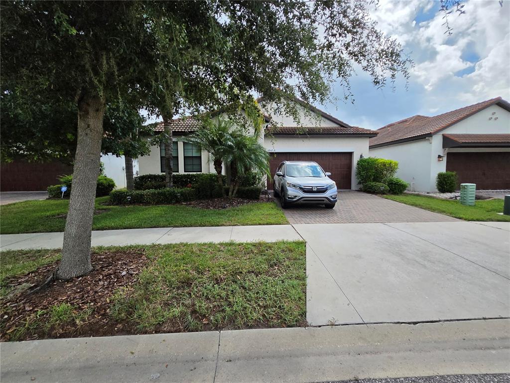 A single-story house with a paved driveway, a silver SUV, and a landscaped front yard — 16842 SCUBA CREST STREET, WIMAUMA, FL