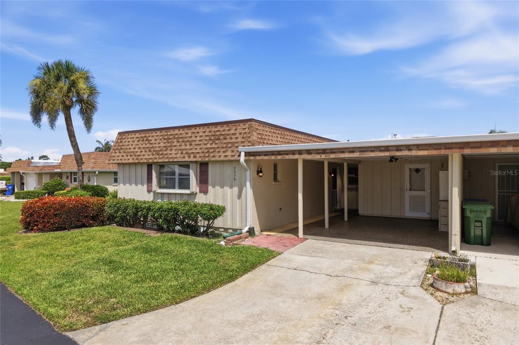 A single-story house with a brown shingled roof, beige siding, and an attached carport — 7206 10TH AVENUE W, BRADENTON, FL