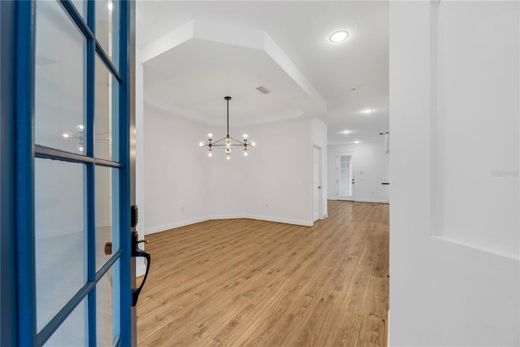 A view through a blue-framed door into a dining area with wood-look flooring — 5320 GOLDEN ISLES DRIVE, APOLLO BEACH, FL