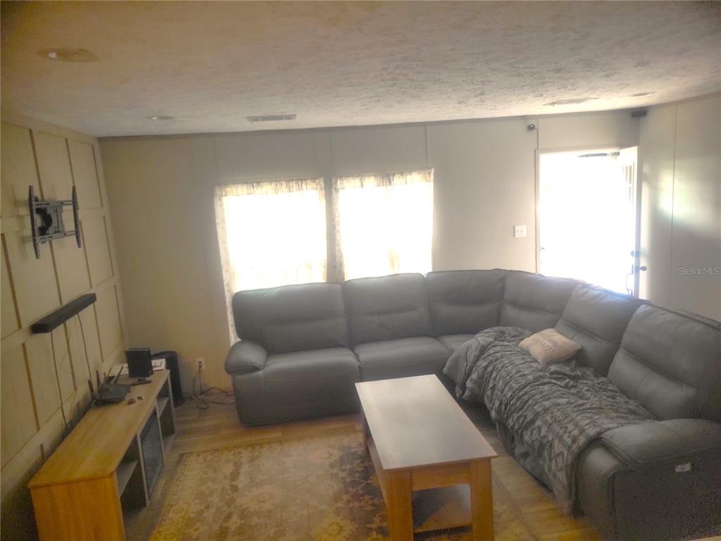 A living room features a large gray sectional sofa, a coffee table, and a media console — 2829 N LAKEFRONT DRIVE, HERNANDO, FL