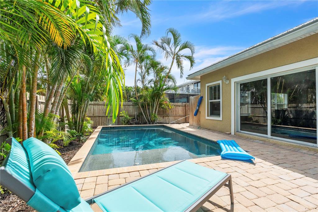 A kitchen with white cabinetry, a large island, and stainless steel appliances opens to a living area — 302 67TH STREET, HOLMES BEACH, FL