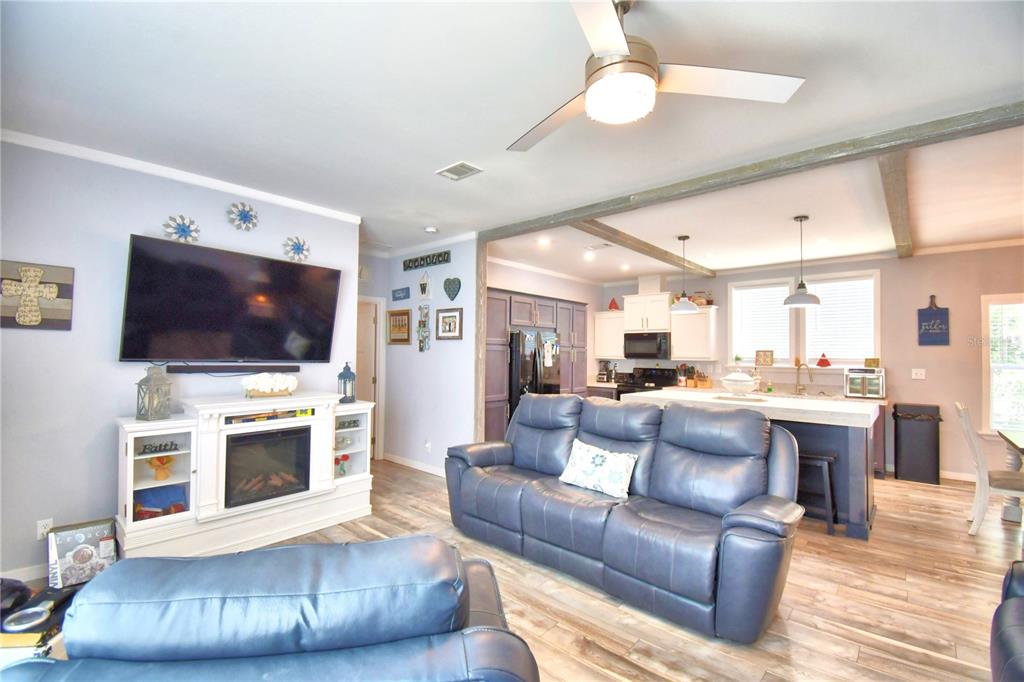 An open-concept living room and kitchen featuring a blue leather sofa and a fireplace — 2497 US HIGHWAY 98 W, FROSTPROOF, FL