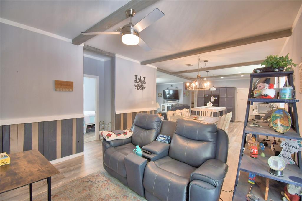 A living room features a gray leather recliner, wood-paneled walls, and an open-concept dining area — 2497 US HIGHWAY 98 W, FROSTPROOF, FL