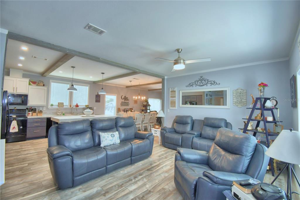 A living room with blue leather furniture opens into a kitchen with white cabinets — 2497 US HIGHWAY 98 W, FROSTPROOF, FL