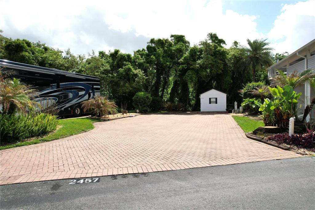 A paved driveway leads to a small white shed in front of a wooded area — 2457 ST GEORGE DRIVE, DAVENPORT, FL