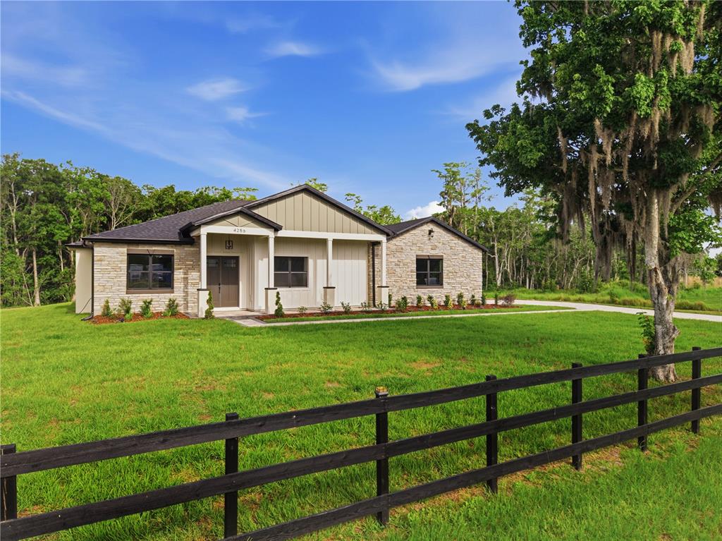 A single-story house with stone and siding exterior sits on a grassy lot near trees — 4256 LA SALLE AVE, ST CLOUD, FL