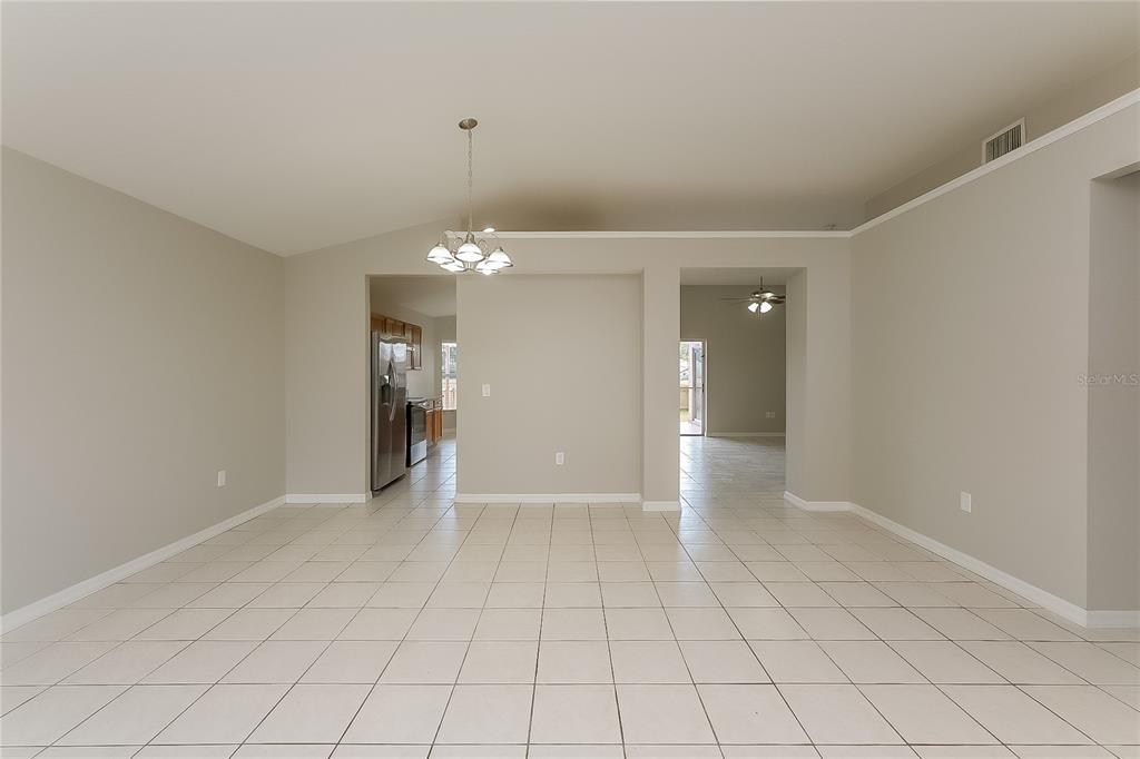 An open-concept dining area features light-colored tile flooring, neutral walls, and a hanging chandelier — 1723 WESTERLY DR, BRANDON, FL
