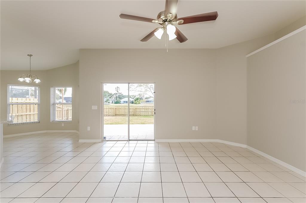 A bright living room features light tile flooring, a ceiling fan, and sliding glass doors — 1723 WESTERLY DR, BRANDON, FL