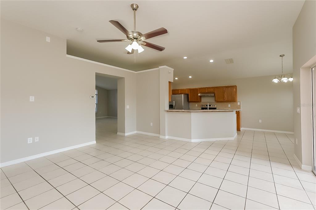 An open-concept living area with tile flooring, a ceiling fan, and an adjacent kitchen — 1723 WESTERLY DR, BRANDON, FL