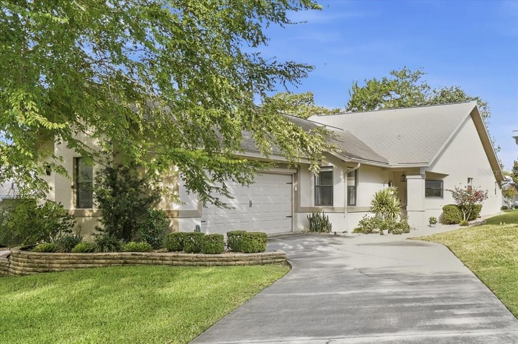 A single-story house with a white stucco exterior, a two-car garage, and a concrete driveway — 58 BYRSONIMA CIRCLE, HOMOSASSA, FL