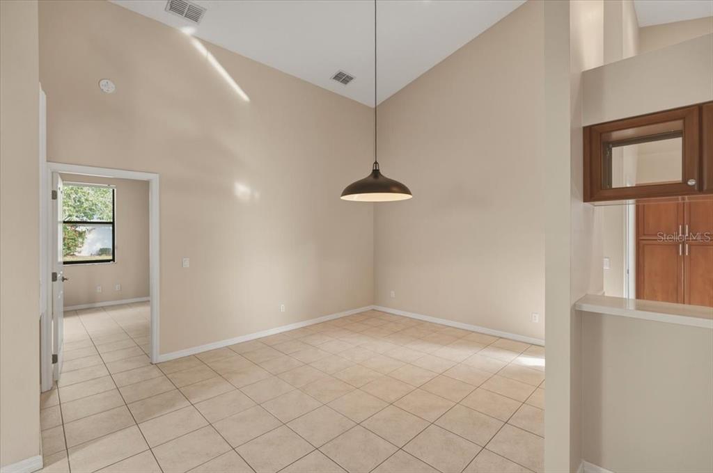 An empty dining room features vaulted ceilings, tile flooring, and a single pendant light fixture — 58 BYRSONIMA CIRCLE, HOMOSASSA, FL