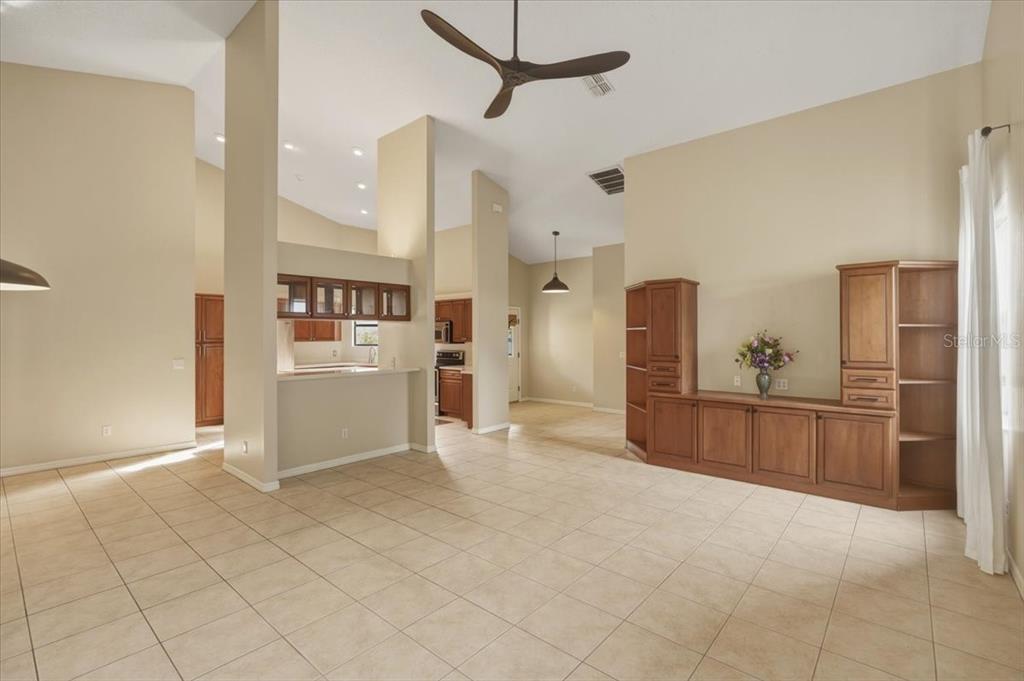 A spacious living area with tile flooring, high ceilings, and built-in wooden cabinetry — 58 BYRSONIMA CIRCLE, HOMOSASSA, FL