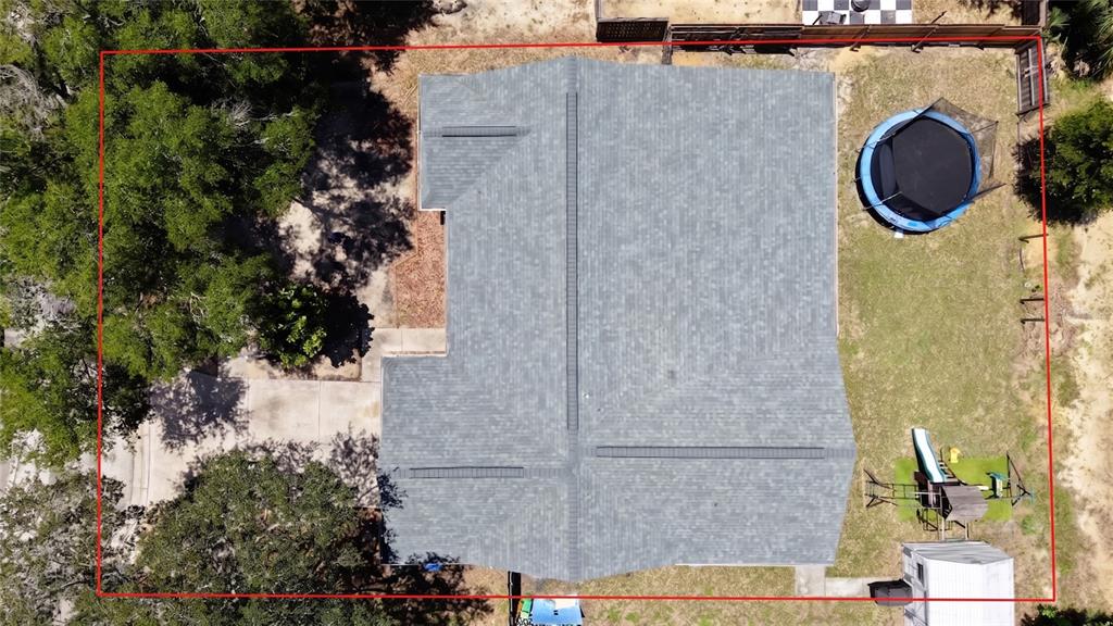 An aerial view shows a house roof, a backyard with a trampoline, and a playground set — 1048 MALLETWOOD DRIVE, BRANDON, FL