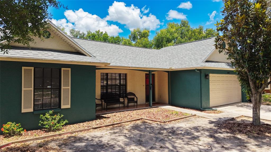 A single-story house with dark green siding, a beige garage, and a covered front porch — 1048 MALLETWOOD DRIVE, BRANDON, FL