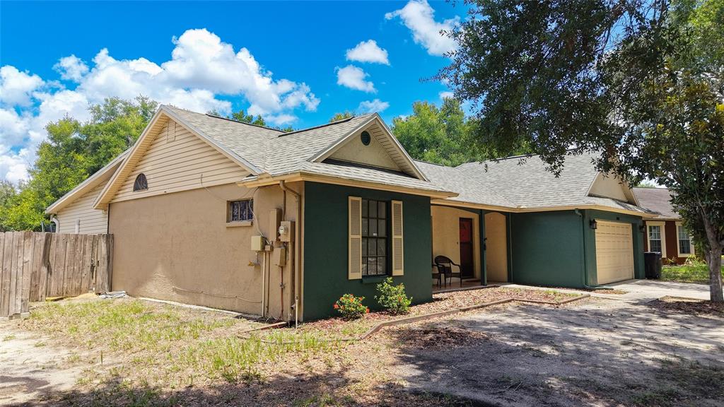A single-story house with a green and tan exterior, a two-car garage, and a wooden fence — 1048 MALLETWOOD DRIVE, BRANDON, FL