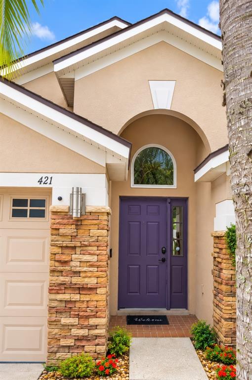 A tan house exterior features a purple front door, stone accents, and a garage — 421 THICKET CREST ROAD, SEFFNER, FL