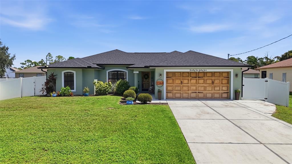 A single-story house with a green exterior, dark shingled roof, and a two-car garage — 2244 PENGUIN LANE, NORTH PORT, FL