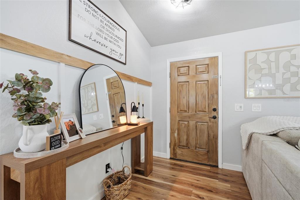 An entryway features a wood console table, a mirror, wall decor, and a wooden front door — 2244 PENGUIN LANE, NORTH PORT, FL