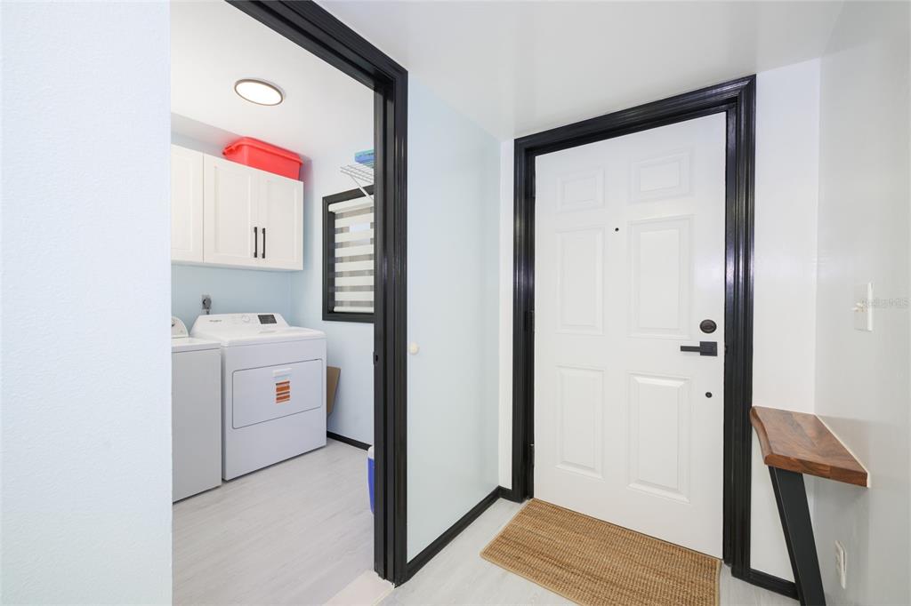 An entryway with a white door and black trim leads into a laundry room — 2220 OCEAN SHORE BOULEVARD UNIT 505A, ORMOND BEACH, FL