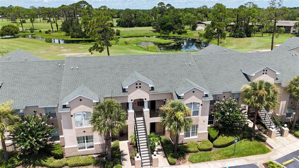 An aerial view shows a multi-story apartment building with a shingled roof and palm trees — 1707 PRESTWICK PLACE UNIT 1707, ST AUGUSTINE, FL