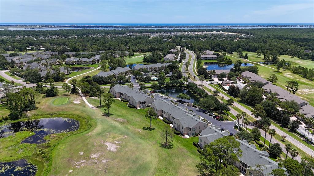 An aerial view shows multi-story apartment buildings surrounded by green space, ponds, and a road — 1707 PRESTWICK PLACE UNIT 1707, ST AUGUSTINE, FL