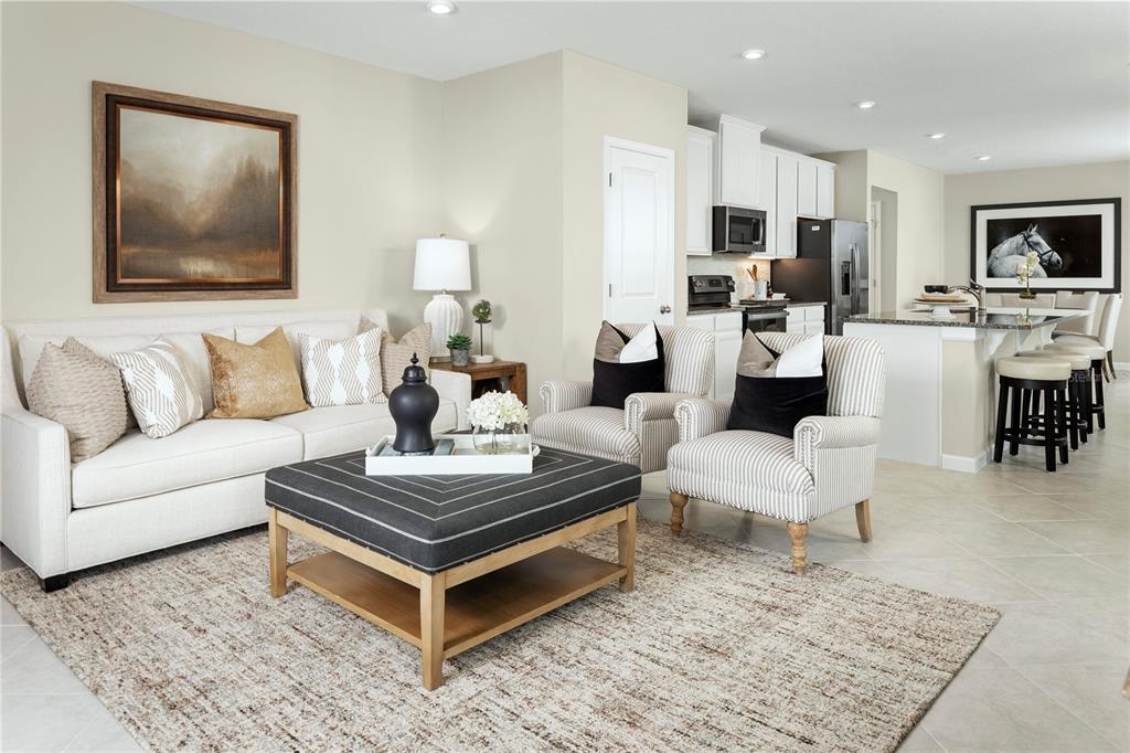 A living room with a sofa, striped armchairs, and a coffee table opens to a kitchen — 2228 SCENIC PARK LOOP, WIMAUMA, FL