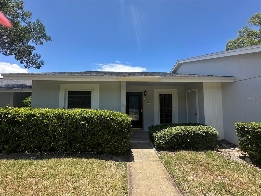 A single-story house exterior features a concrete walkway leading to a covered front entrance — 12423 DEARBORN DRIVE UNIT E, HUDSON, FL