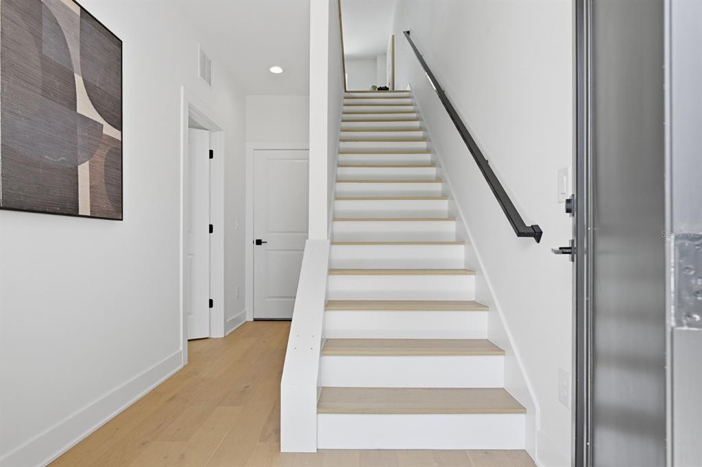 A bright entryway features a wooden staircase with white risers and a black handrail — 310 W COLUMBUS DRIVE UNIT 3, TAMPA, FL