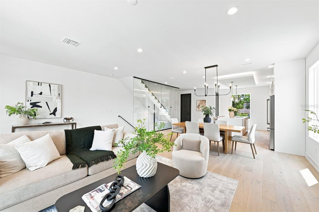 An open-concept living and dining area features light wood floors, white walls, and glass-enclosed stairs — 310 W COLUMBUS DRIVE UNIT 3, TAMPA, FL