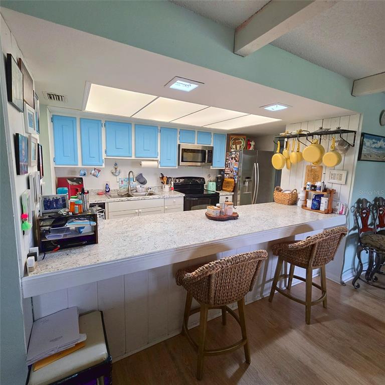 A kitchen with light blue cabinets, a long breakfast bar, and wicker stools — 512 2ND STREET UNIT 5, INDIAN ROCKS BEACH, FL