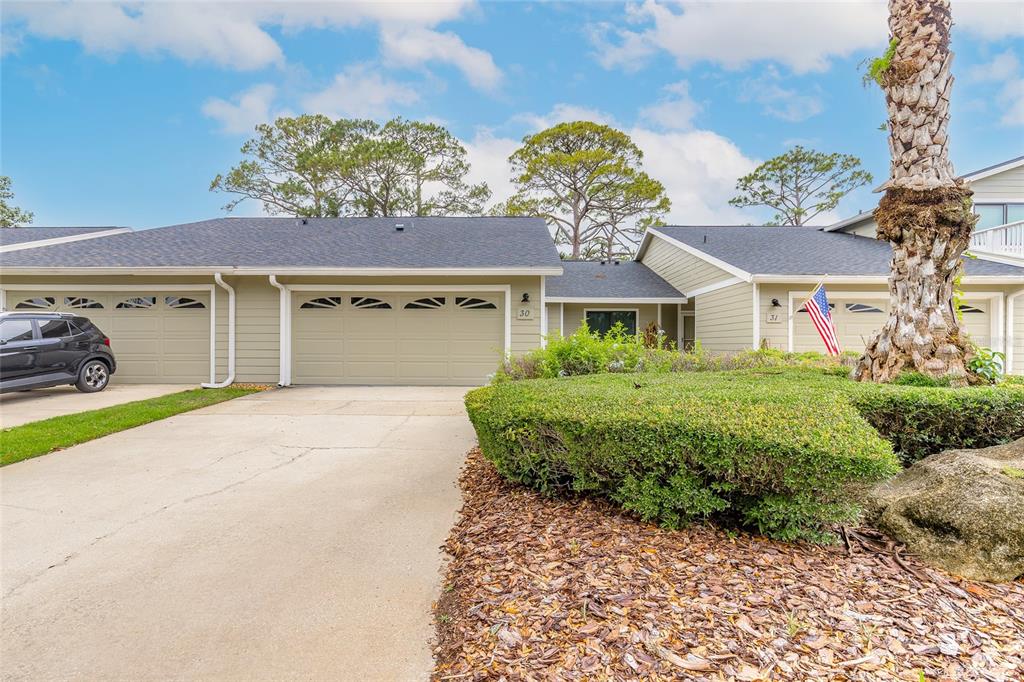 The exterior of a single-story townhouse features a two-car garage and a landscaped front yard — 30 LANDINGS LANE UNIT 30, ORMOND BEACH, FL