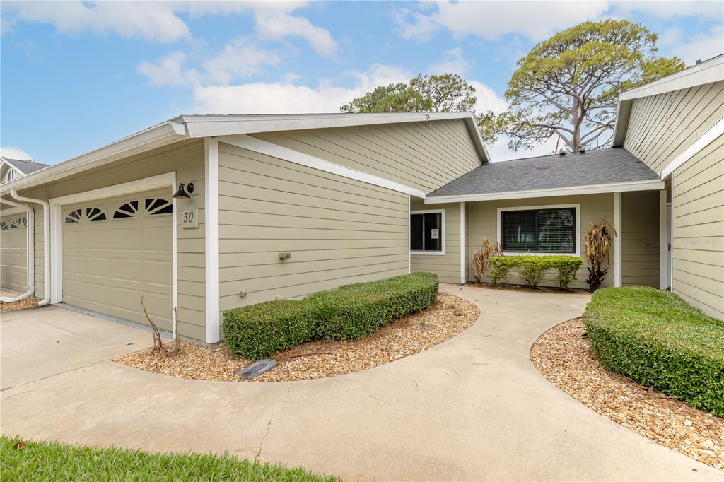 A single-story house with light green siding, a two-car garage, and a curved concrete walkway — 30 LANDINGS LANE UNIT 30, ORMOND BEACH, FL