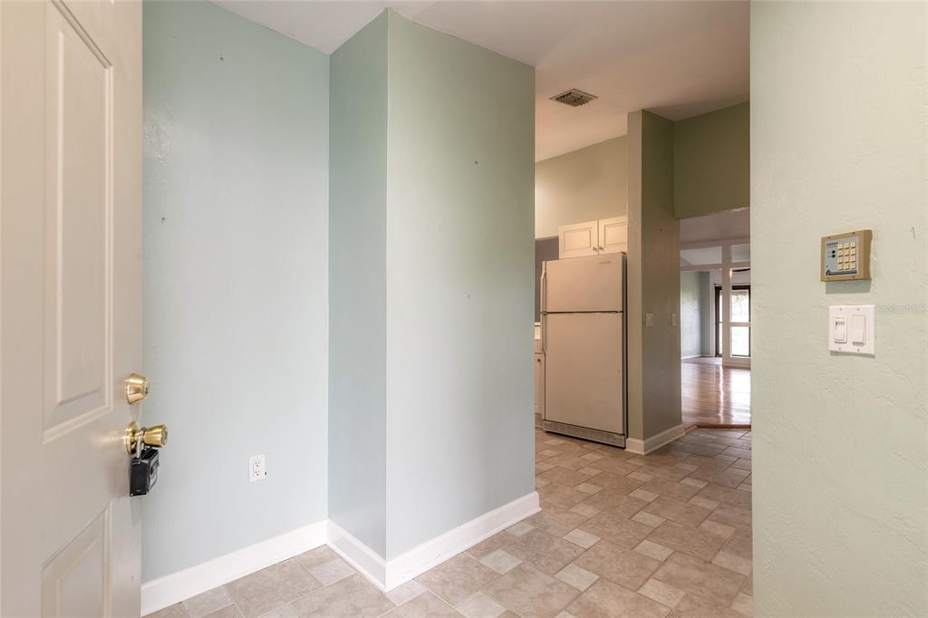 An entryway leads to a kitchen with a white refrigerator and tiled flooring — 30 LANDINGS LANE UNIT 30, ORMOND BEACH, FL