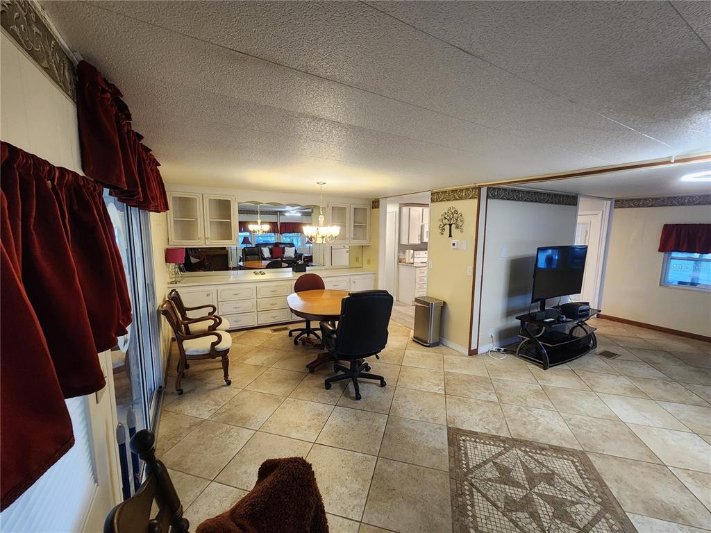 A dining area with tile floors, a round table, and a built-in buffet with mirrors — 808 53RD AVENUE E UNIT 110, BRADENTON, FL