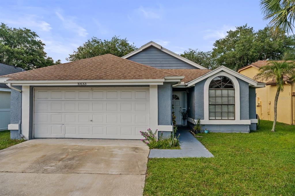 A single-story house with a blue exterior, a two-car garage, and a front arched window — 10133 MARGUEX DRIVE, ORLANDO, FL