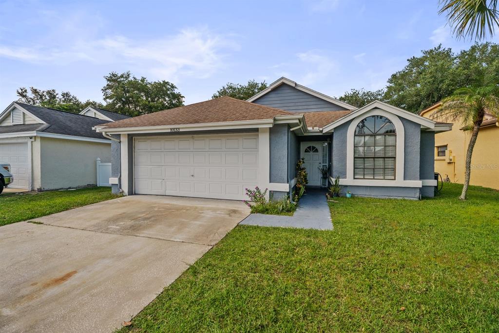 A single-story house with a white garage door, gray siding, and an arched front window — 10133 MARGUEX DRIVE, ORLANDO, FL