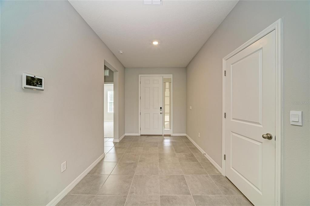 A tiled entryway features a white front door, a side door, and light gray walls — 11007 TAMARACK PLACE, PARRISH, FL