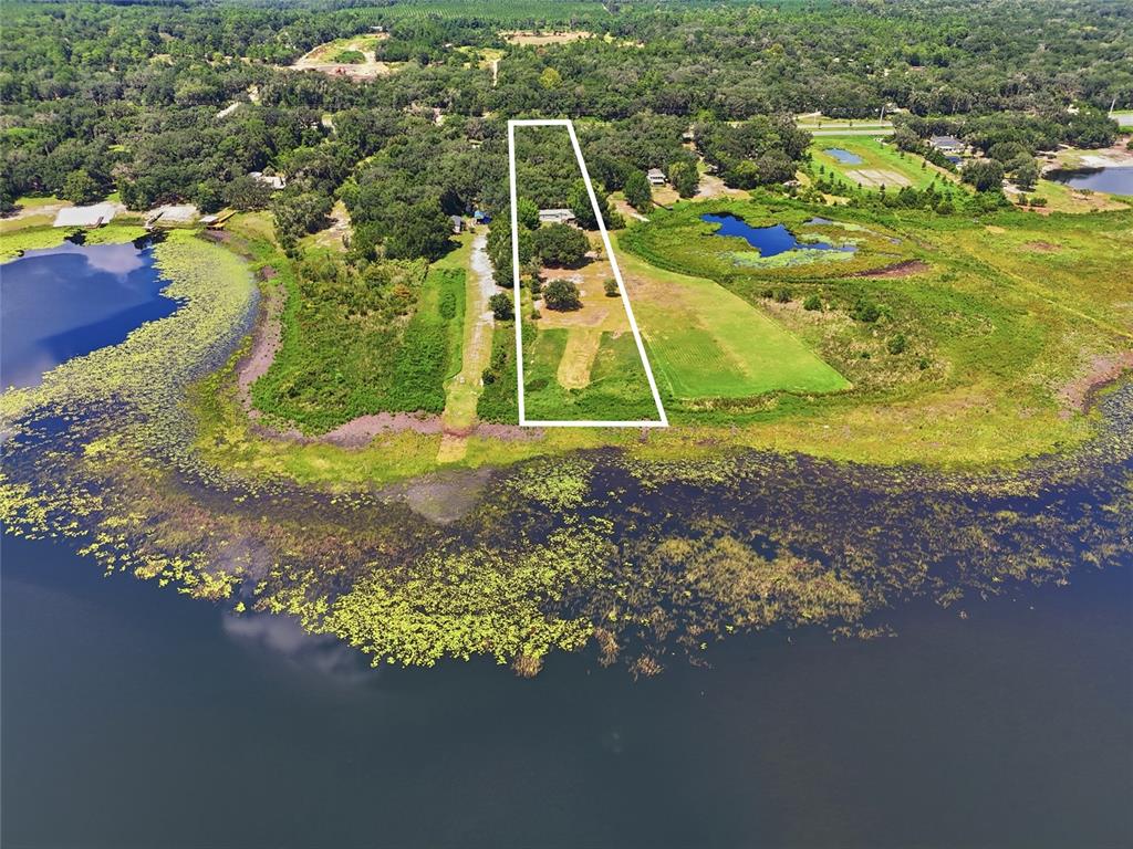 An aerial view shows a trapezoidal property lot bordering a large lake with vegetation — 1837 STATE ROAD 20, HAWTHORNE, FL