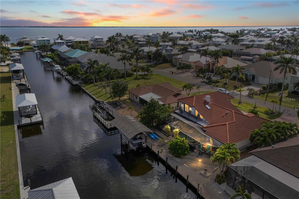 An aerial view shows a waterfront house with a pool, boat dock, and canal access — 2420 CHERIMOYA LANE, ST JAMES CITY, FL