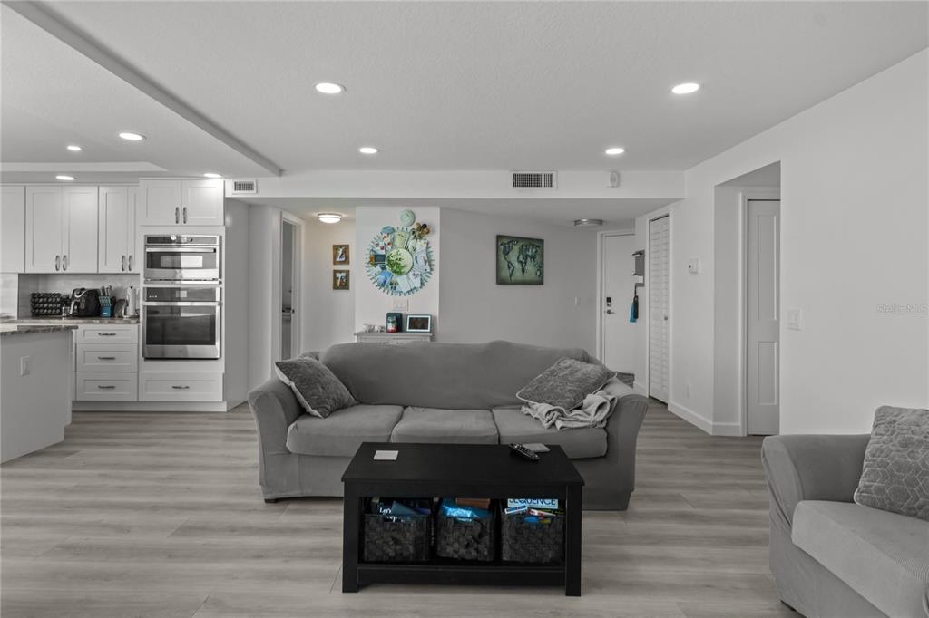 A living room features gray sofas, light wood-look flooring, recessed lighting, and a television — 5505 LA PUERTA DEL SOL BOULEVARD S UNIT 126, ST PETERSBURG, FL
