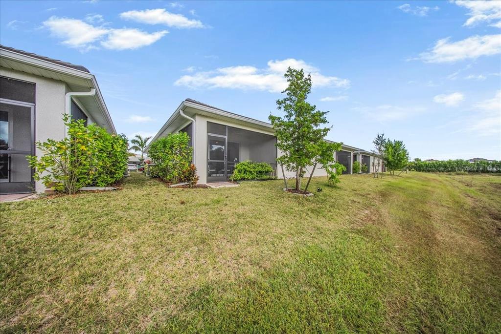 The exterior view shows the screened-in back patios of several adjacent single-story residential units — 1074 ENBROOK LOOP, NAPLES, FL