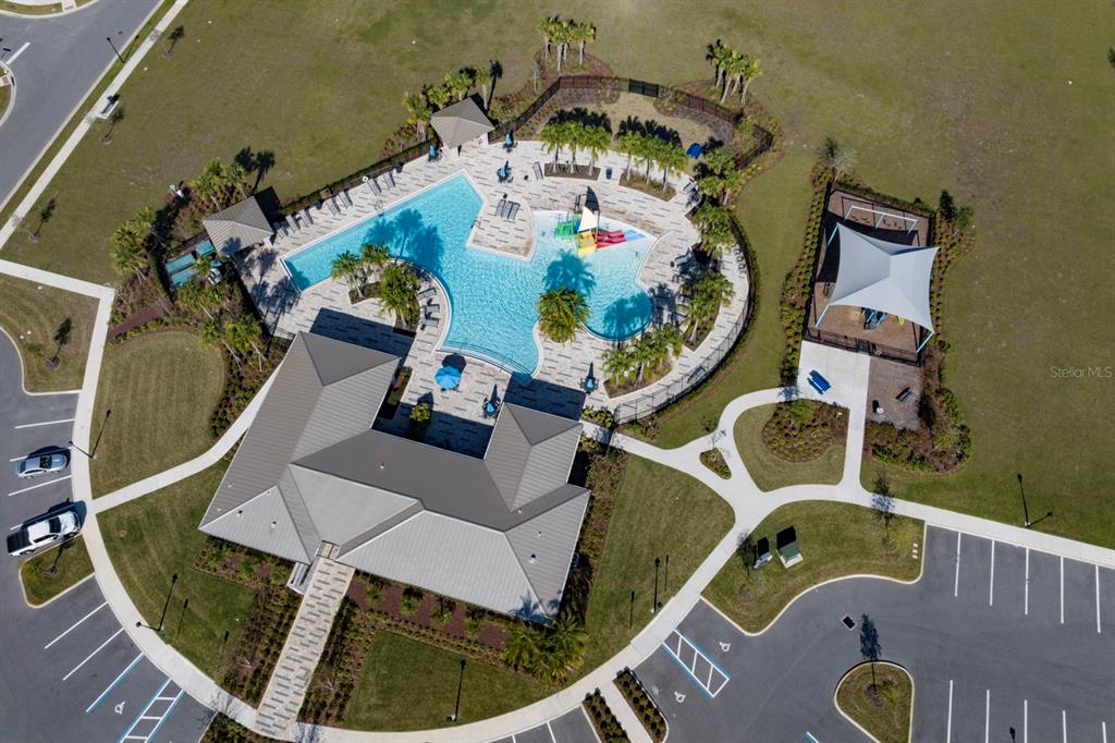 An aerial view shows a community swimming pool, clubhouse, and parking lot — 7040 ROLLING LEAF ROAD, GROVELAND, FL