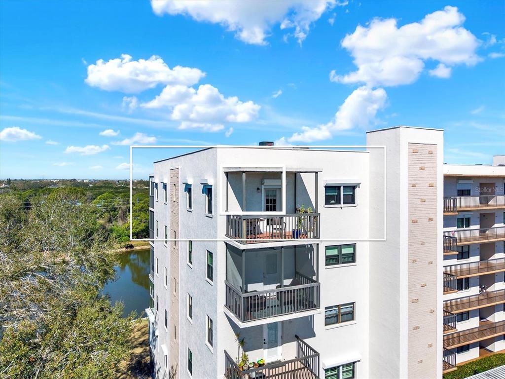An exterior view of a multi-story apartment building featuring stacked balconies and a lake view — 8186 TERRACE GARDEN DRIVE N UNIT 601, ST PETERSBURG, FL