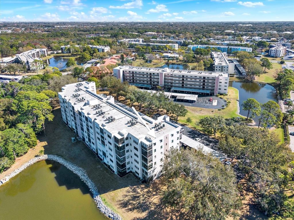 An aerial view shows two multi-story apartment buildings situated near ponds and wooded areas — 8186 TERRACE GARDEN DRIVE N UNIT 601, ST PETERSBURG, FL