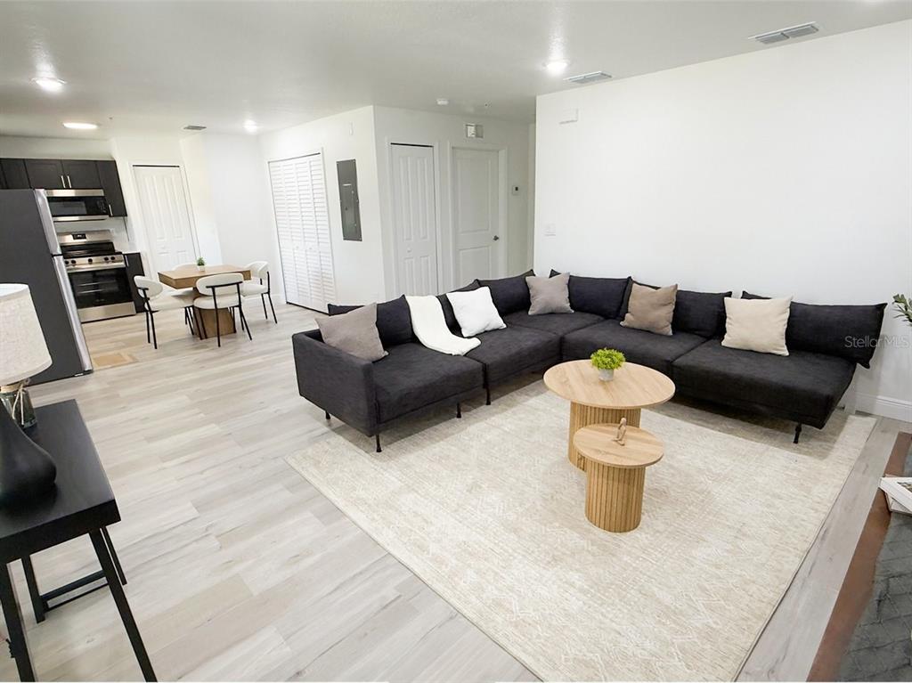 A living room with a large sectional sofa, coffee tables, and an adjacent open-concept kitchen — 2201 CONWAY DRIVE UNIT 201, DELTONA, FL
